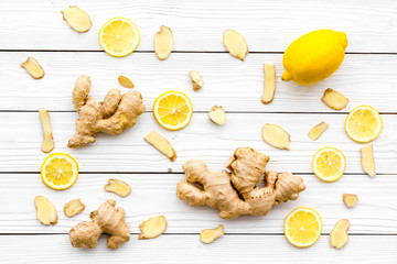 Ingredient for warming tea. Whole and sliced ginger roots, lemon on white wooden background top view