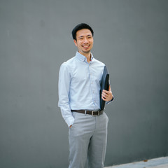 An image of a successful Chinese Asian man, dressed in a professional outfit. He is standing...