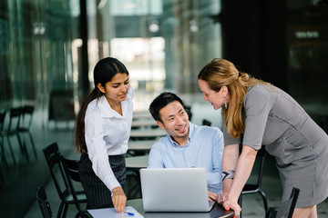 A diverse multi-racial team of three colleagues businesspeople have a relaxed discussion around a...