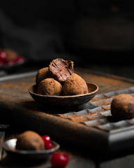 Chocolate truffle. Dark chocolate and cherry candy sprinkled with cocoa on a dark wooden background in rustic style. Atmospheric food photo.  Homemade fresh energy balls.