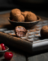 Chocolate truffle. Dark chocolate and cherry candy sprinkled with cocoa on a dark wooden background in rustic style. Atmospheric food photo.  Homemade fresh energy balls.
