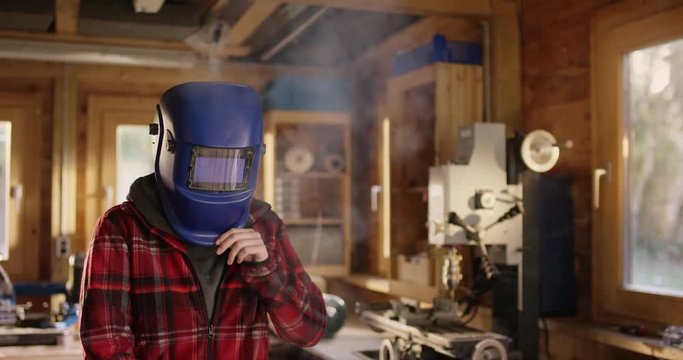 Young attractive woman welds metal in a workshop