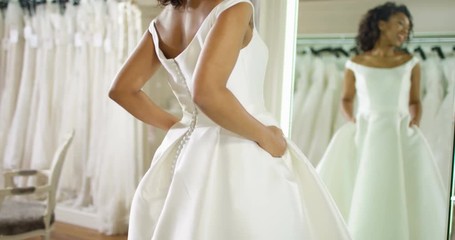 4K Beautiful bride trying on her dress in wedding shop & admiring her reflection in the mirror. Slow motion.