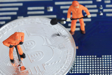 Model people of miners are standing on the silver bitcoin.