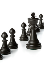 King chess figure in front of row of pawn chess figures