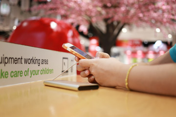 hands of a women playing a smartphone on wooden table.