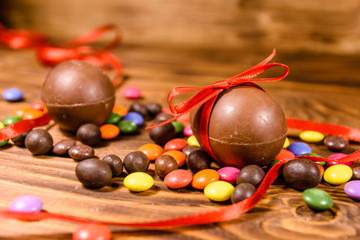 Chocolate easter eggs and multicolored candies on wooden table