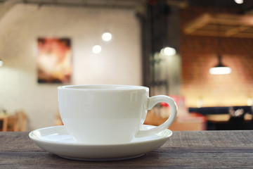 White Coffee cup on wooden table in coffee shop blur background.