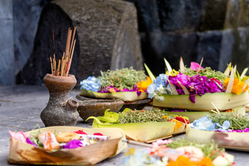 Burning incense sticks surrounded with Balinese offerings outside on a footpath. Seminyak, Bali, Indonesia.