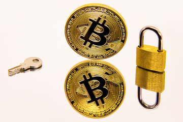 Conceptual image of a cryptocurrency bitcoin coin on a white mirror surface with a golden padlock and key