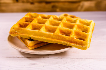 Ceramic plate with belgian waffles on wooden table