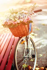 Fotobehang Fiets met mand met lentebloemen in park in de buurt van bank in zonlicht bij zonsondergang of zonsopgang. Begin van het nieuwe seizoen van kortingen. © Gennadiy Poznyakov