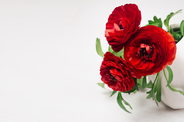Deep red flower bouquet in vase with copy space on white wood background. Festive summer backdrop.