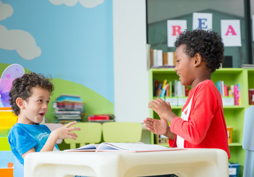 Two boy kid sit on table and coloring in book  in preschool library,Kindergarten school education concept.