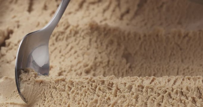 Slow motion closeup hazelnut praline ice cream scooping with spoon