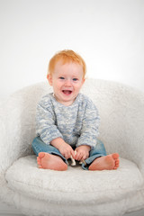 Fototapeta premium Kid sits on a white plush armchair