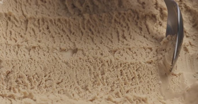 Slow motion closeup hazelnut praline ice cream scooping with spoon