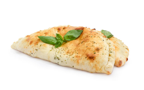 Two cooked calzone with basil twigs on a white background