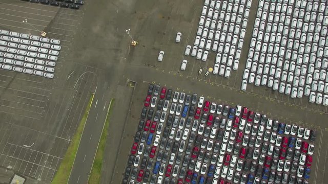 Forward flight looking down at large parking lot with new imported cars at Port Melbourne