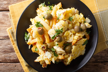 Portuguese food: fried shredded cod with french fries, onions and eggs close-up. horizontal top view