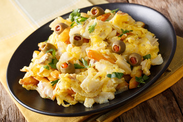 Bacalhau Bass - roasted cod, potatoes, onions and egg in a plate closeup. Horizontal