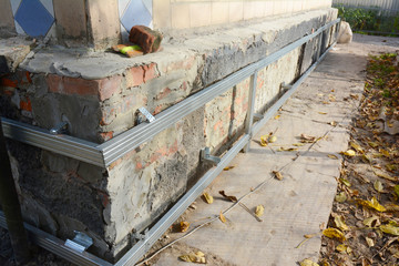 House foundation wall repair,  renovation  with installing metal sheets on metal frame for waterproofing and protect from wetness.