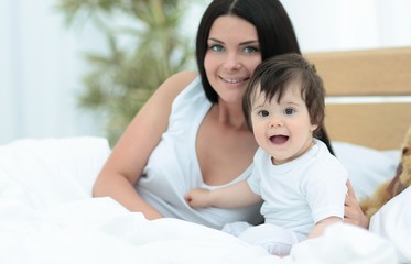 Portrait of a beautiful mother with her baby in the bedroom