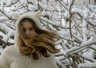 Portrait of beautiful teenage girl in snow.  Long hair blows in wind. Winter theme.