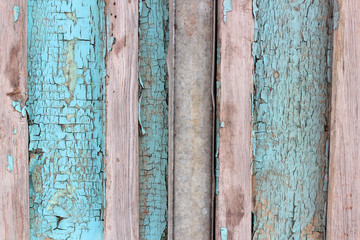 Background texture pattern of weathered wooden planks with grungy remnants of blue paint forming the siding of an exterior building wall