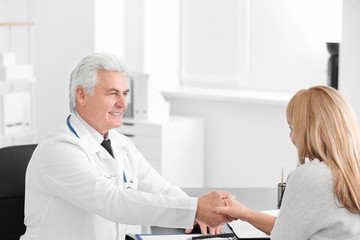 Obraz premium Male doctor and patient shaking hands during consultation in clinic