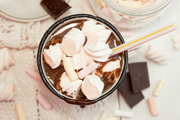 Mug of hot chocolate drink with marshmallow candies on top and chocolate chips on white background.