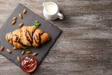 Delicious croissant with chocolate and jam on slate plate