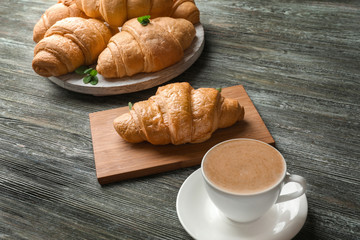 Delicious croissants with cup of coffee on wooden table