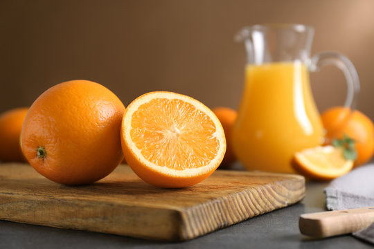 Wooden board with juicy ripe oranges on table