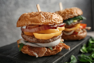 Wooden board with tasty burger on table