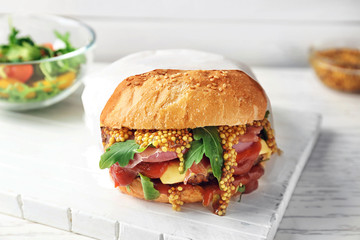 Tasty burger with mustard on wooden board