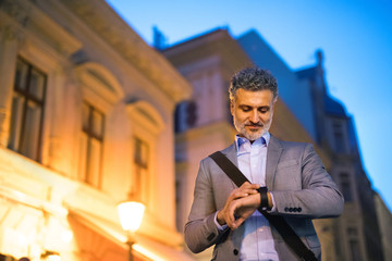 Mature businessman with a smartwatch in a city.