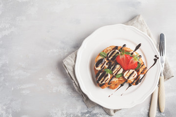 French toasts with chocolate syrup, strawberries and banana. Gray background, copy space, top view.