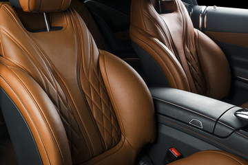 Modern Luxury car inside. Interior of prestige modern car. Comfortable leather seats. Orange perforated leather cockpit with isolated Black background. Modern car interior details