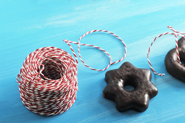Gingerbread in chocolate in the form of a star. Near the coil with packing tape. Blue wood background. Close-up. Macro photography.