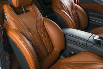 Modern Luxury car inside. Interior of prestige modern car. Comfortable leather brown seats. Orange perforated leather cockpit with isolated Black background. Modern car interior details