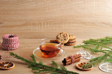 Christmas composition. In the frame, oatmeal cookies with chocolate chips, tea, spruce branches, spices, Christmas toys, slices of dry orange and a coil with braid. Light wooden background. Close-up.