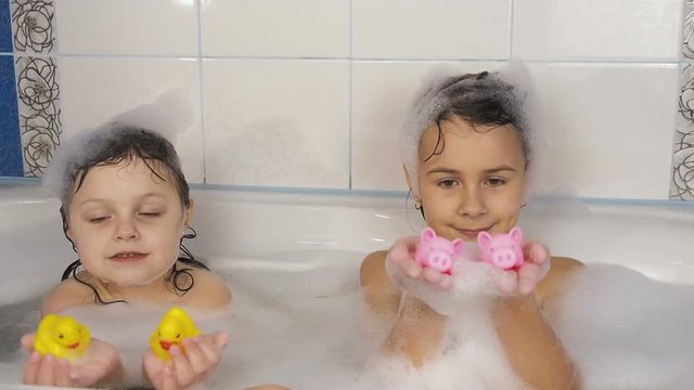 Children take a bath. Little girls play with toys in the bathroom.