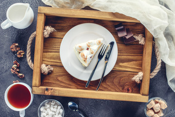 top view of delicious piece of cake with meringue on plate on wooden tray