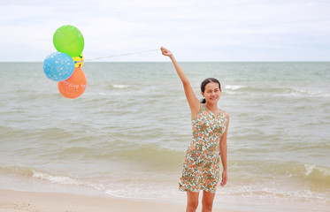 Happy woman holding balloon on beach on vacation. Holiday concept.