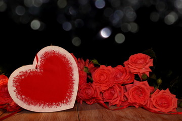 Obraz na płótnie Canvas красивая розовая роза и фигурка сердца на черном фоне на деревянных досках 