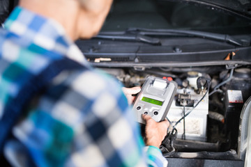 Senior female mechanic repairing a car in a garage.