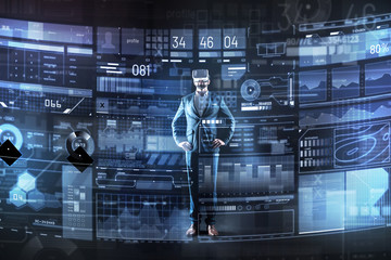Obraz premium Wonderful technologies. Calm qualified smart programmer feeling satisfied with his virtual reality glasses and using them while being in his modern office