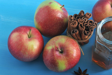 Composition with ripe apples, a jar of honey, anise and a bunch of cinnamon stick. Blue wood background. View from above. Close-up. Macro photography.