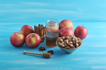Composition with ripe apples, a bowl of hazelnuts, a jar of honey, anise and cinnamon sticks. Blue wood background. Close-up.